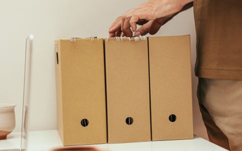 一只手正在整理桌面上的牛皮纸文件收纳盒